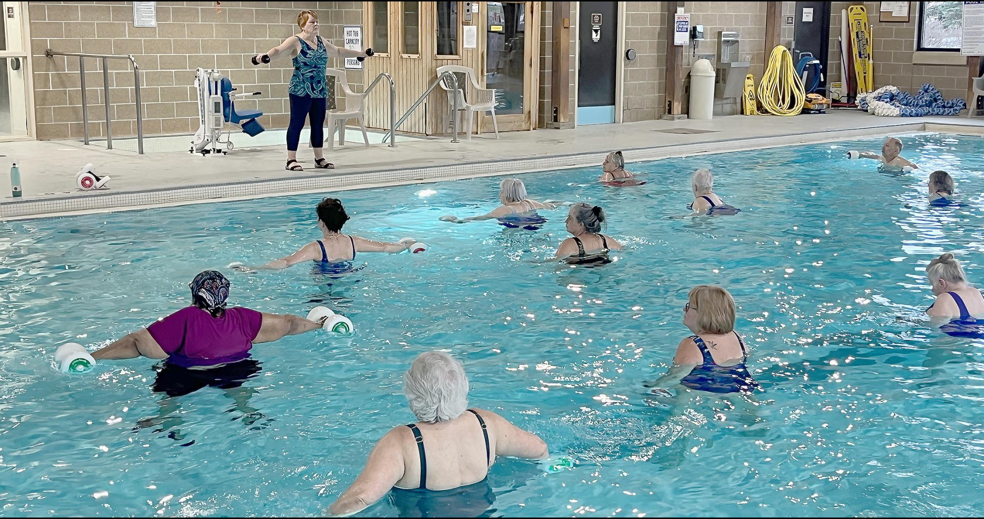 Members doing water exercise with styrofoam weights